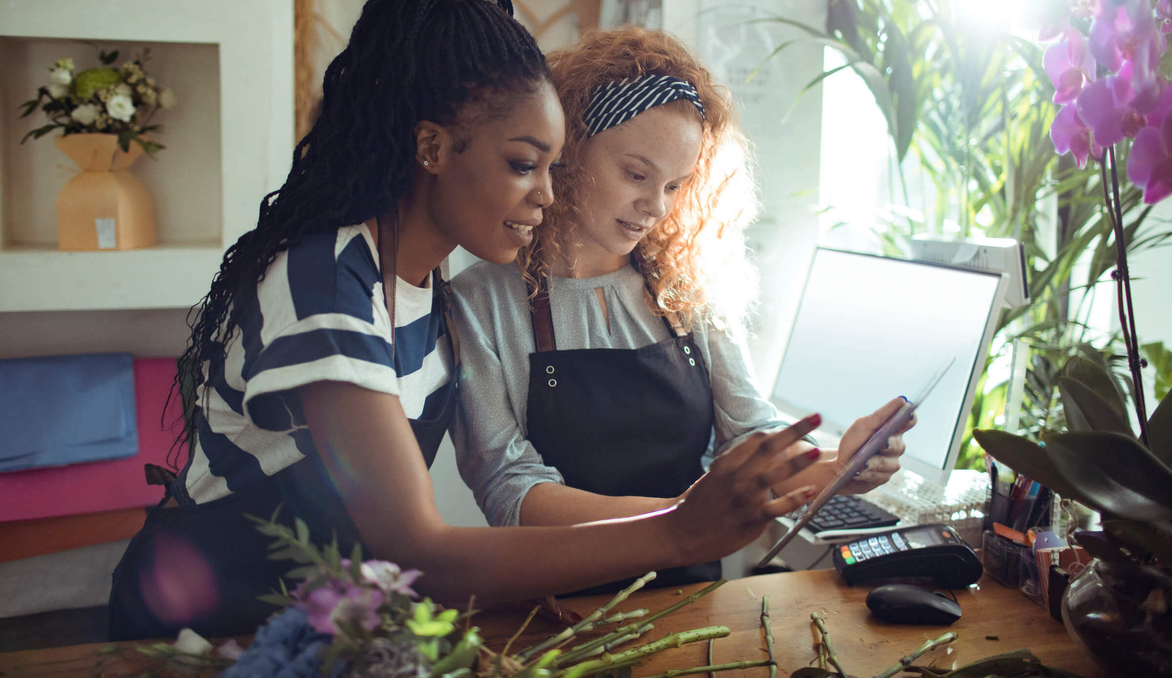 Two women discussing business loans on a tablet