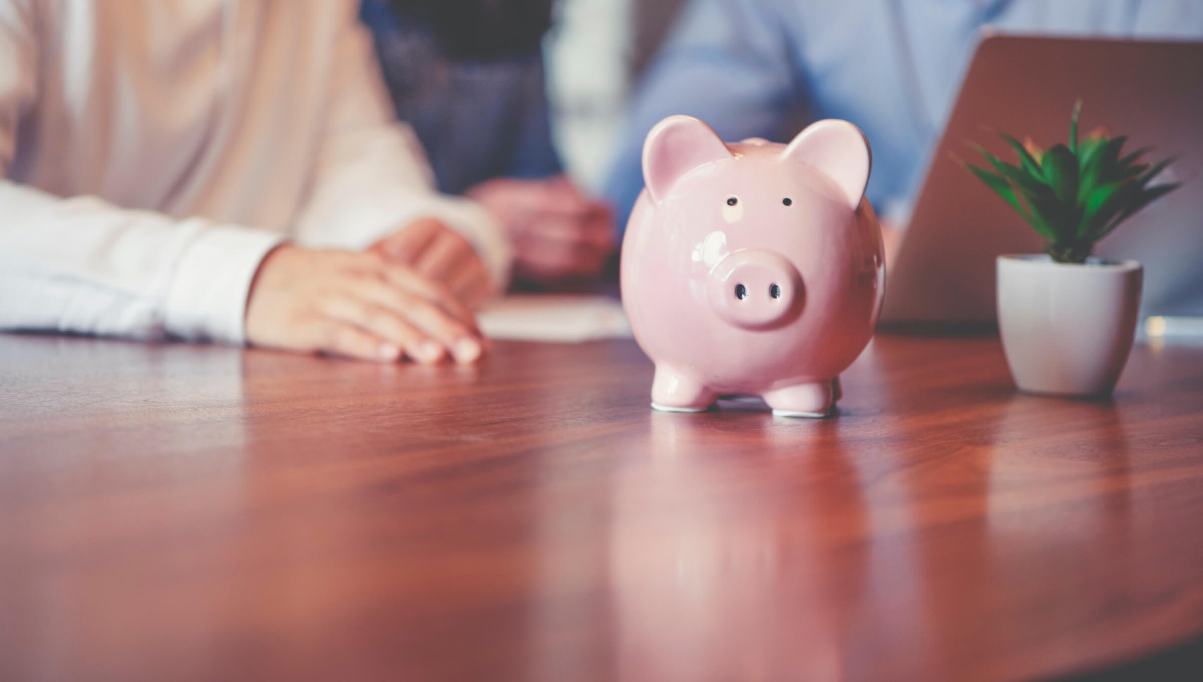 piggy bank on table as people discuss business loan